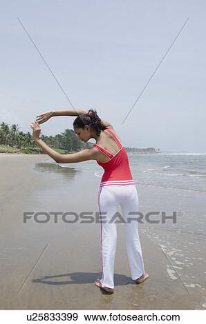 Rear view of a young woman exercising on the beach View Large Photo Image Stock Photo - Rear view of a young woman exercising on the beach. Fotosearch