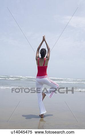 Rear view of a young woman standing in a tree pose on the beach View Large Photo Image Stock Photography - Rear view of a young woman standing in a tree pose on the beach. Fotosearch