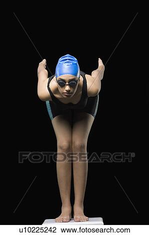 Stock Image - Young woman taking position on a starting block. Fotosearch
