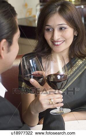 Close-up of a mid adult man with a young woman holding glasses of wine in a restaurant View Large Photo Image Stock Image - Close-up of a mid adult man with a young woman holding glasses of wine in a restaurant. Fotosearch