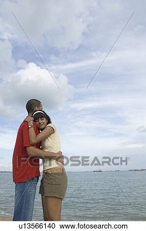 Mid adult woman and a young man embracing each other on the beach View Large Photo Image Stock Image - Mid adult woman and a young man embracing each other on the beach. Fotosearch