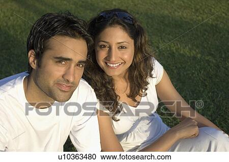 Portrait of a young couple sitting in a garden and smiling View Large Photo Image Stock Image - Portrait of a young couple sitting in a garden and smiling. Fotosearch