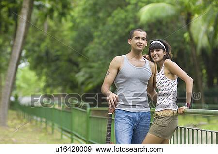 Portrait of a young couple standing in a park and smiling View Large Photo Image Stock Photo - Portrait of a young couple standing in a park and smiling. Fotosearch
