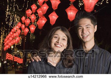 Stock Photograph - Portrait of a young man with his arm around a young woman and smiling. Fotosearch