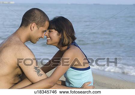 Stock Photograph - Side profile of a couple hugging on the beach. Fotosearch