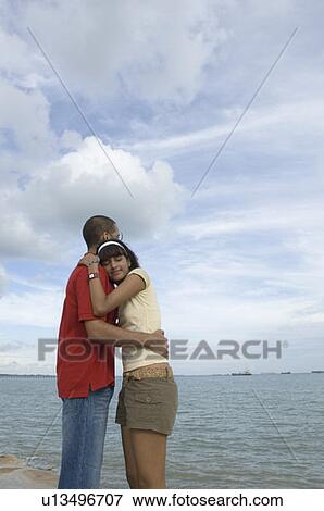 Side profile of a young couple embracing each other on the beach View Large Photo Image Stock Photo - Side profile of a young couple embracing each other on the beach. Fotosearch