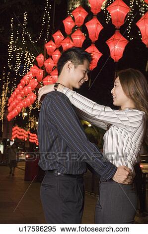 Stock Photography - Side profile of a young couple embracing each other and smiling. Fotosearch