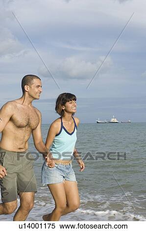 Stock Photography - Young couple running on the beach. Fotosearch