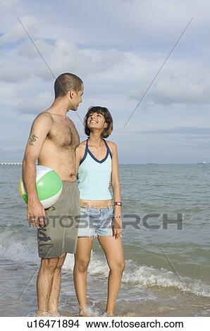 Young couple standing on the beach with a beach ball View Large Photo Image Picture - Young couple standing on the beach with a beach ball. Fotosearch