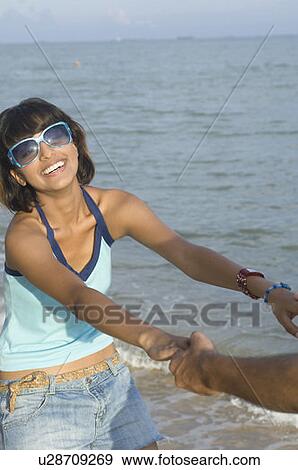 Stock Photo - Young woman playing on the beach with a man. Fotosearch