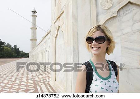 Stock Image - Close-up of a young woman smiling in front of a mausoleum, Taj Mahal, Agra, Uttar Pradesh, India. Fotosearch