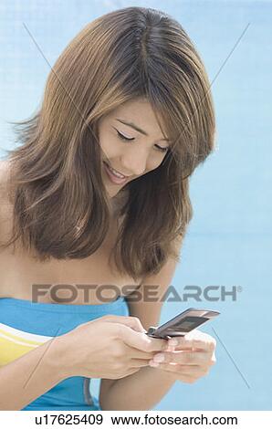 Close-up of a young woman using a mobile phone View Large Photo Image Stock Photo - Close-up of a young woman using a mobile phone. Fotosearch