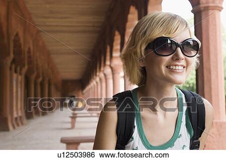 Stock Photograph - Close-up of a young woman wearing sunglasses and smiling, Taj Mahal, Agra, Uttar Pradesh, India. Fotosearch