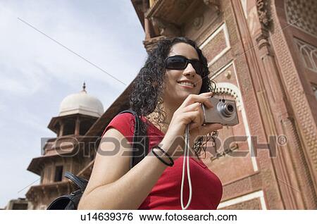 Low angle view of a young woman holding a digital camera and smiling, Taj Mahal, Agra, Uttar Pradesh, India View Large Photo Image Stock Photograph - Low angle view of a young woman holding a digital camera and smiling, Taj Mahal, Agra, Uttar Pradesh, India. Fotosearch