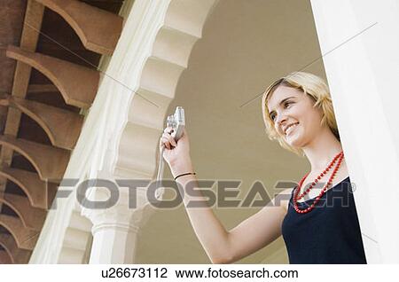 Stock Image - Low angle view of a young woman taking a picture with a digital camera, Taj Mahal, Agra, Uttar Pradesh, India. Fotosearch