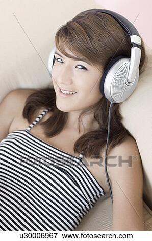 Stock Photo - Portrait of a young woman listening to music and smiling. Fotosearch