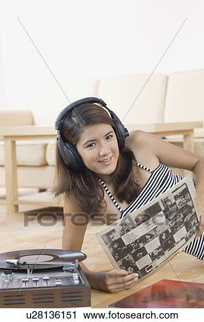 Stock Image - Portrait of a young woman reclining on a hardwood floor and listening to music. Fotosearch
