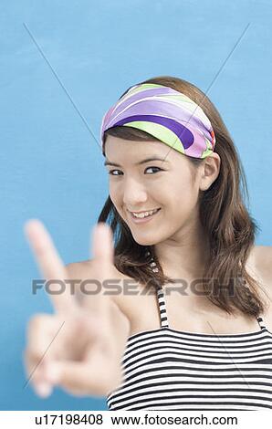 Portrait of a young woman showing a peace sign View Large Photo Image Stock Photo - Portrait of a young woman showing a peace sign. Fotosearch