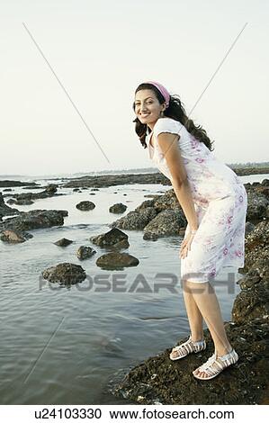Portrait of a young woman standing on a rock and smiling View Large Photo Image Stock Image - Portrait of a young woman standing on a rock and smiling. Fotosearch