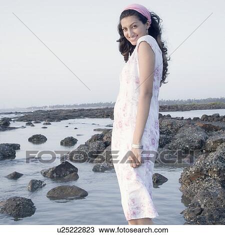 Portrait of a young woman standing on the beach and smiling View Large Photo Image Stock Image - Portrait of a young woman standing on the beach and smiling. Fotosearch